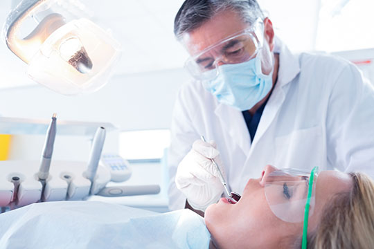 Un dentiste examine les dents de sa patiente.