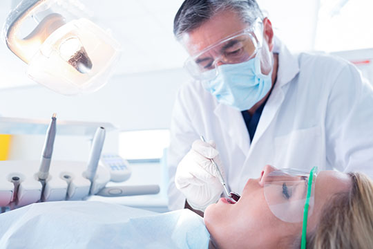 Dentist examining a patients teeth in the dentists chair at the dental clinic.