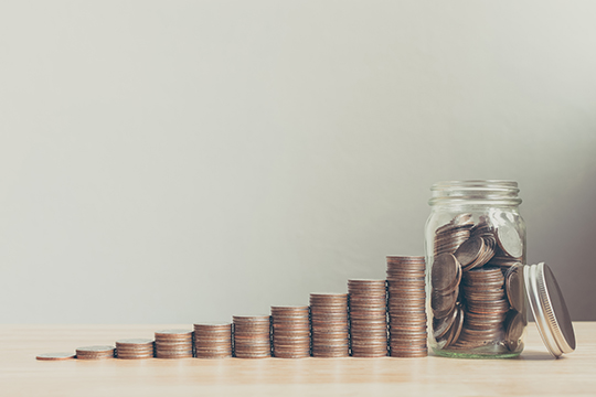 Coins in glass jar next to accumulating coin stacks. Coins in glass jar next to accumulating coin stacks.