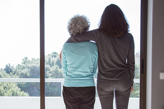 Mother and daughter looking out a window