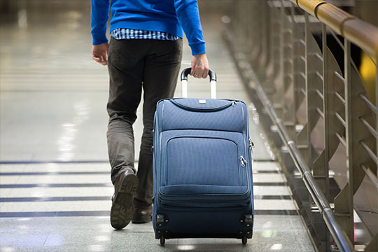 Person traversing an airport walk with luggage.