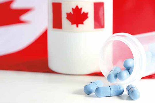 Tasse avec le drapeau canadien à côté d'un flacon de pilules renversé.