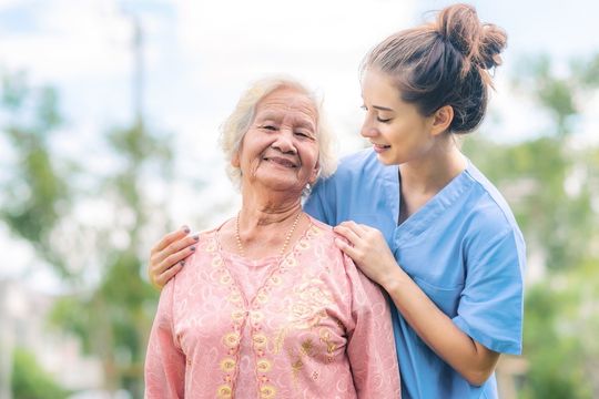 Smiling caregiver on a walk with long-term care resident.