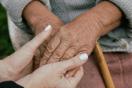 Résidente d’un établissement de soins à long terme tenant la main d’une proche aidante