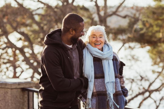 Adult man caregiver with woman patient outdoors.