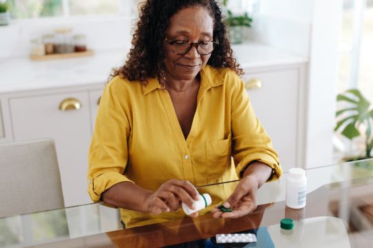 Woman opening pill bottle.