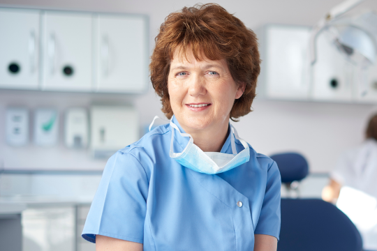 Adult dentist standing in her office.