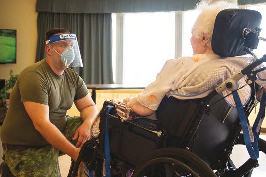 Soldier attending to a senior in a wheelchair.