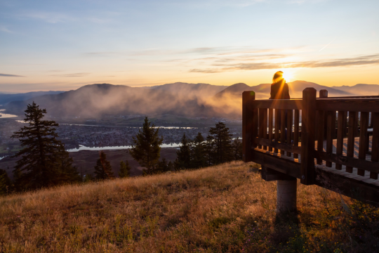 Femme adulte debout à un belvédère avec vue sur Kamloops, en Colombie-Britannique.