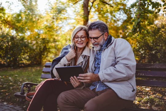 Adult couple sitting together with a tablet device.