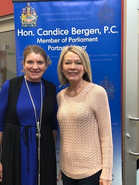 Two women stand in front of a blue roll-up background MB32 president Leanne Coleman-Kamphuis with local member of Parliament Candace Bergen.