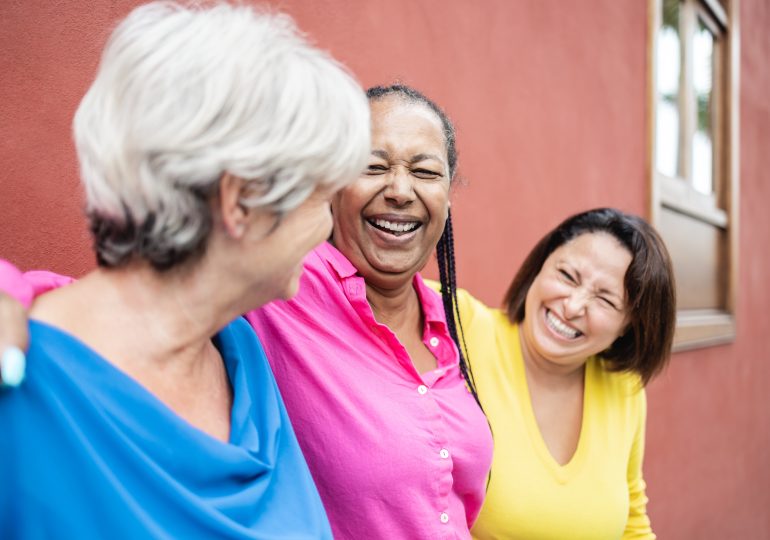 Three adult women friends standing together.