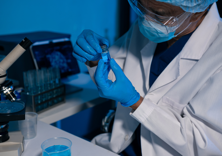 Chercheur portant un équipement de protection en laboratoire et examinant des échantillons liés à la recherche sur les maladies infectieuses.